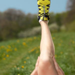 closeup of male stretching leg with yellow running shoe outdoors